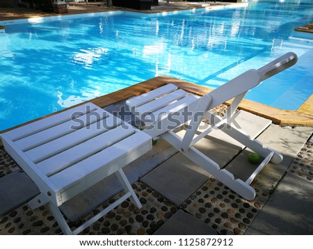 White wooden table and chair beside the swimming pool.