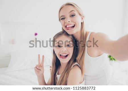 Indoors domestic lifestyle grimace fooling concept. Close up portrait of cute cool funky funny beautiful pretty excited rejoicing delightful mom and offspring making taking self picture in bed room
