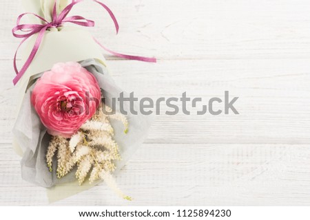 Ranunculus bouquet closeup, leafs, twigs on white wooden background. Concept for workshop or celebration. Shabby chic style