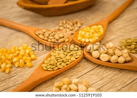 Wooden spoon with some grains. Beans, Corn, Lentils and Chickpeas at Wood Background