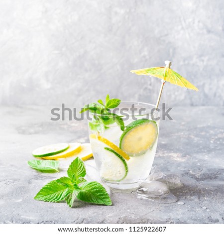 A refreshing cocktail of lemon lime and mint leaves with ice in a glass goblet on a gray background. Summer drink lemonade. Selective focus. Copy space