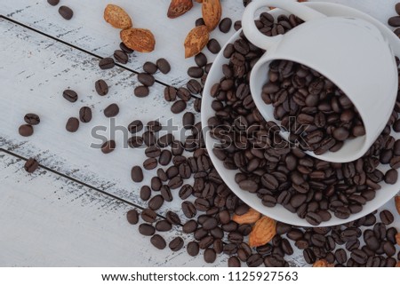 Cup of coffee with coffee beans on white wooden table.