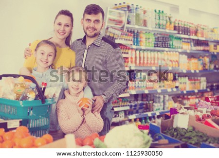 Adult parents with two girls choosing sweet citrus fruits in food store