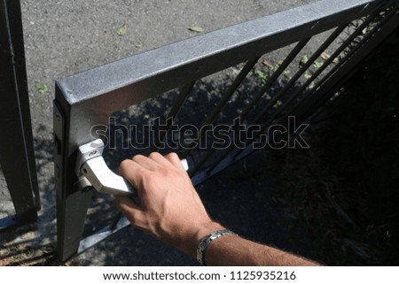 Man opens gate view from above. Hand on door handle