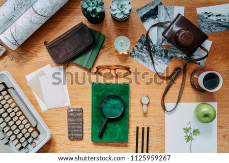 Modern composition of  wooden desk with typewiter, photos, notebook, retro camera , map and office accessories. Creative desk of traveler and adventure man. 