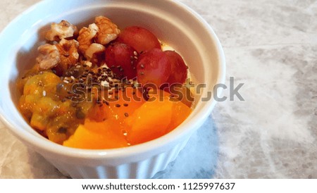 mixed fruits with kefir grains served with ceramic bowl and placed on a marble table