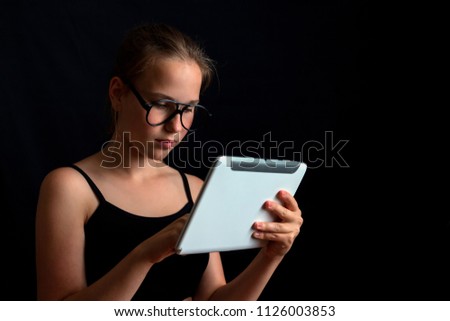 Girl in glasses working at a computer on a dark background with copy space