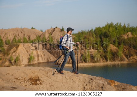 Image of tourist man in cap with walking sticks on mountain hill