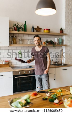 Image of man with frying pan in hands in kitchen