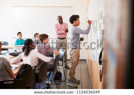 View Through Doorway Of High School Pupil Writing On Whiteboard In Class Royalty-Free Stock Photo #1126036049
