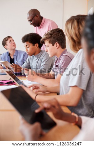 High School Teacher With Pupils Using Digital Tablets In Technology Class