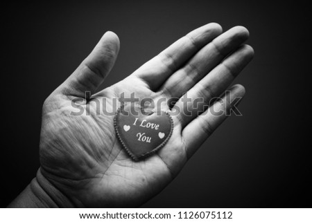 Hand holding the red heart symbol with word I Love You. Black and white vintage background image.  
