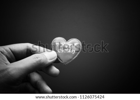 Hand holding the red heart symbol with word Happy Birthday. Black and white vintage background image.  