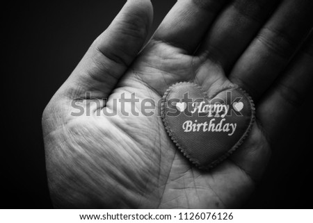 Hand holding the red heart symbol with word Happy Birthday. Black and white vintage background image.  