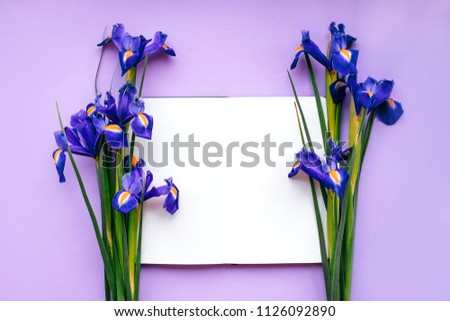 Blank notebook with beautiful iris flowers on the violet background.