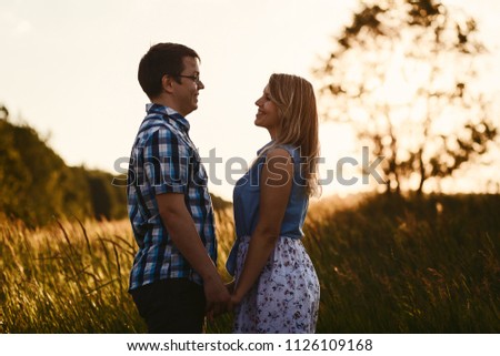 happy lovers look at each other outdoors, guy and girl holding hands