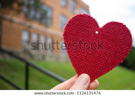 Craft red heart in front of school hand holding