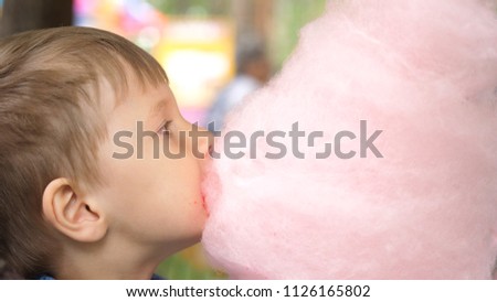 Baby eating cotton candy in the Park. Sweet and airy dessert