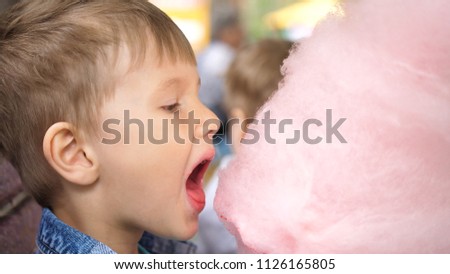 Baby eating cotton candy in the Park. Sweet and airy dessert. The day of the birth of the child.