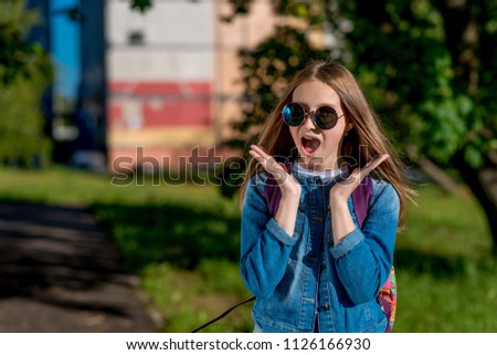 Girl schoolgirl teenager. Summer in nature. In jeans clothes, sunglasses. The concept of surprise, surprises, gift, surprise. Emotions of joy of happiness and delight, Scream and exclamations.