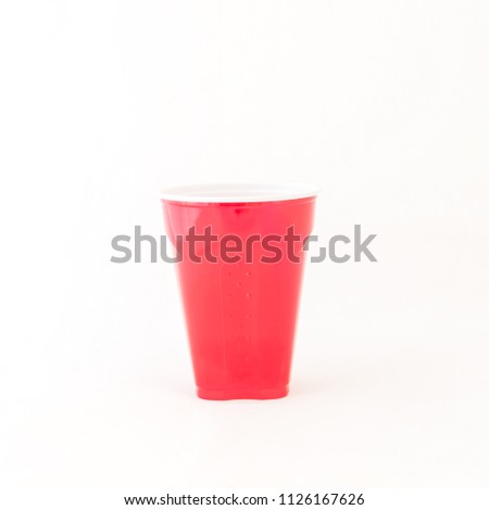 Studio shot one disposable party cup isolated on white background. Red picnic cup recycle mug close-up with clipping path and copy space