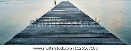 Dawn on a wooden jetty stretching into the silent ocean