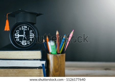 Education concept - books,alarm clock,clay earth,congratulation cap on the desk.
