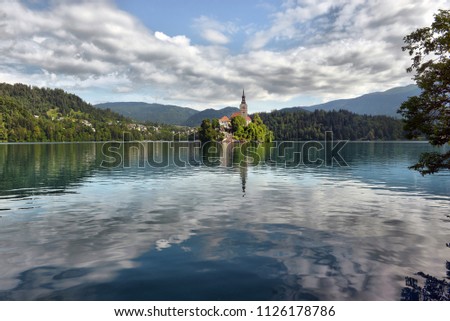 Lake Bled with St. Marys Church of Assumption on small island. Bled Slovenia Europe. Mountains and valley on background. Staircase stairs lead to church