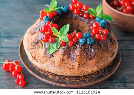 Homemade chocolate cake with chocolate icing, mint  and fresh berries. Soft focus.