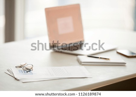 Office table with laptop and documents on desk, modern workplace with paper report or business plan and corporate devices, glasses for vision correction during computer work or reading concept