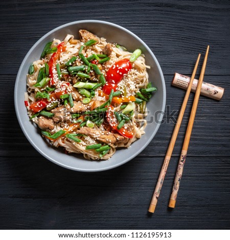 Thai noodle and chicken in the grey plate on a black wooden background with chopsticks