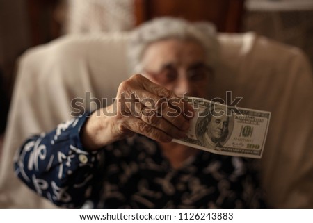 Portrait of elderly woman holding dollar in hands.