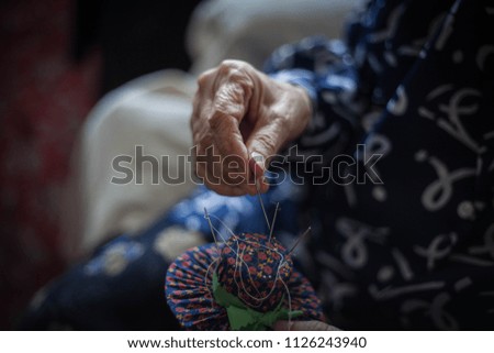 Close up of grandmothers hand holding needle.