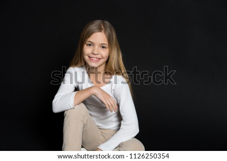 Happy child with fashion hairstyle on black background. Little girl smile with long blond hair. Beauty kid smiling with adorable look. Beauty salon. Keep calm and get your hair done.