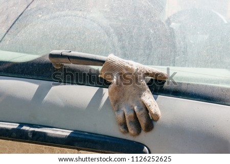 The glove on the wiper blade. Cleaning dirty glass on the car