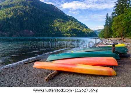 Row of colorful kayaks lying on the shore of Lake Crescent on late afternoon, Olympic National Park, Washington State, USA. Royalty-Free Stock Photo #1126275692