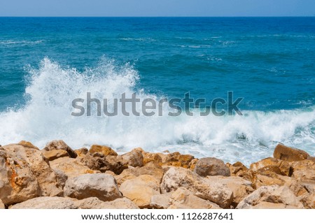 Blue sea surf wave on a bright yellow stones. Blue sea and spray on a Sunny day on the shore