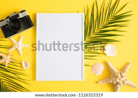 Front view blank mock up of photo frame.Tropical palm leaves branches on yellow background, camera, starfish. Travel vacation concept. Summer background. Flat lay, top view, copy space
