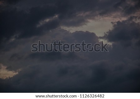 Light holes in the dark storm clouds before a thunder-storm. The image contains noise and artifacts to give a more sinister picture.The clouds are multilevel and diverse.