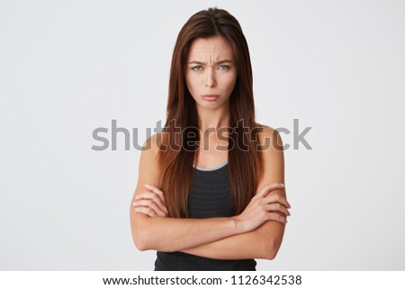 Sad upset young woman with long hair stnding with arms crossed and looking offended isolated over white background Feels disappointed