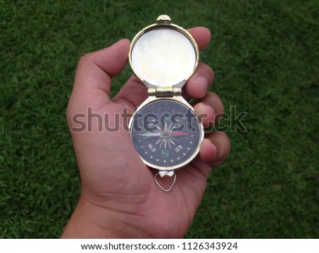 Hand holding compass isolated on green background