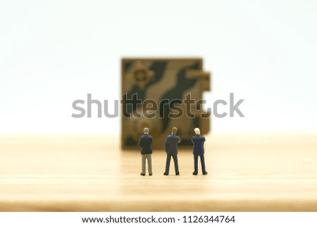 Miniature businessmen standing Investment Analysis Security Key Repair And the treatment of the precious. on white background using as background business concept and Security concept with copy space.