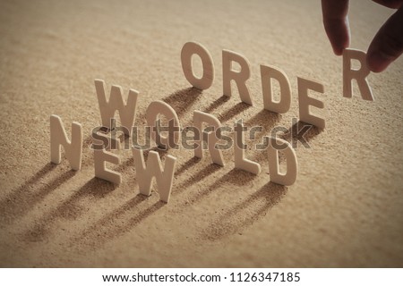 NEW WORLD ORDER wood word on compressed or corkboard with human's finger at T letter.
 Royalty-Free Stock Photo #1126347185
