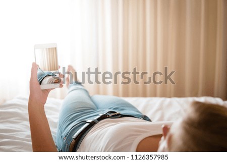 Woman in bed taking a picture of the view from her bedroom