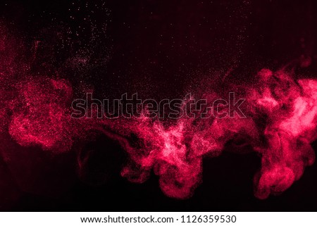 The explosion of red dust on a black background.