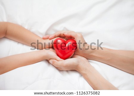 Mother's Day celebration with woman holds young kid's hands supporting red heart gift, and charity donation for nursing children concept. Royalty-Free Stock Photo #1126375082
