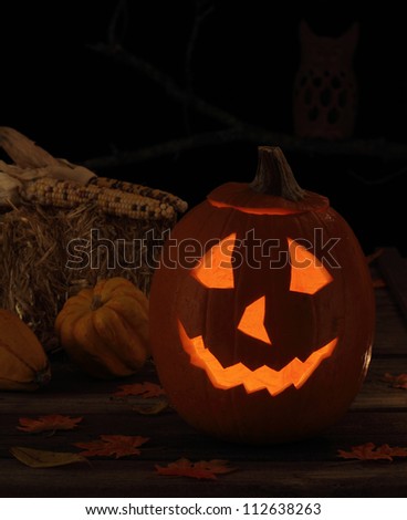 Smiling jack-o-lantern with autumn decorations on a black background
