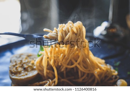 The spaghetti was delicious, hot smoke, use a fork to eat in a restaurant , soft focus.