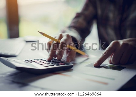 Business woman holding a pencil to analyze the marketing plan with calculator on wooden table at office. Accounting concept.Finance concept. Royalty-Free Stock Photo #1126469864