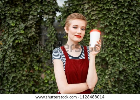 a woman with a glass of light is standing near green bushes                              